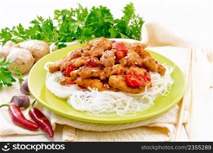 Stir-fry chicken with pepper, garlic, ginger and soy sauce, sprinkled with sesame seeds in a plate, napkin and parsley on white wooden board background