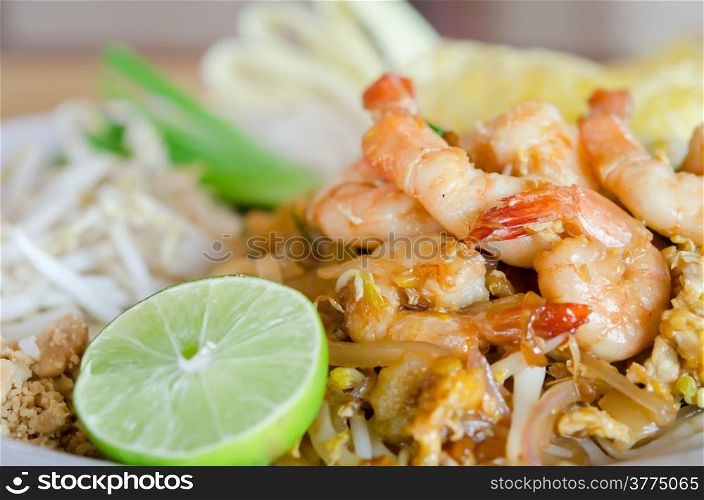 Stir fry noodles with shrimp , egg and vegetable served with fresh lemon and fresh vegetable