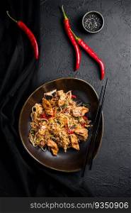 Stir fry noodles with vegetables and chicken in a black bowl