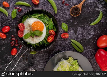 Stir kale and fried egg in a pan with tomatoes and red beans.