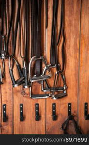 Stirrup iron & stirrup leather hanging on the wooden wall.