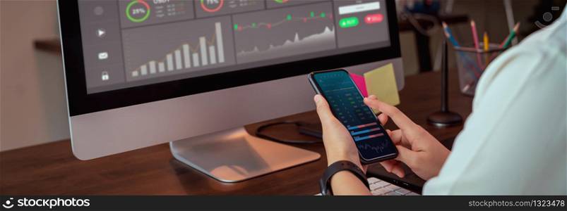 Stock exchange market concept, businesswoman trader looking on smartphone and computer with graphs analysis candle line on table in office, diagrams on screen. proportion of the banner for ads.
