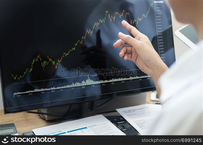 Stock exchange trader Analyzing Graphs chart or data On Multiple Screens in office