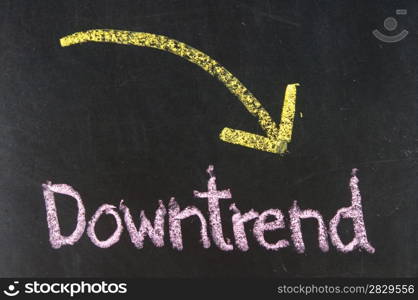 Stock Exchange word DOWNTREND made with chalk on a blackboard.