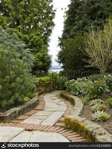 Stone and Brick Pathway through woods to Lake with overcast sky in background