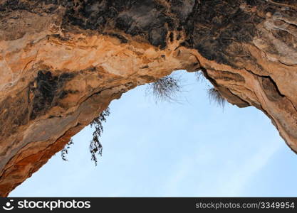 Stone arch of the cave exit on sky background