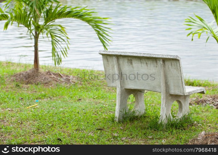 Stone bench in the grass. Adjacent to the pool in the park.