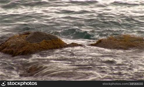 Stone boulders under sea waves.