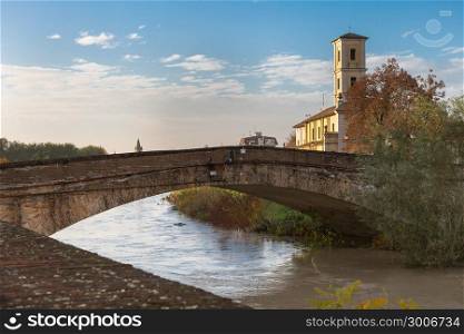 Stone Bridge over the River and Ancient Bell Tower in Colorno, Parma, Emilia Romagna region, Italy.. Stone Bridge over the River and Ancient Bell Tower in Colorno, Parma, Emilia Romagna region, Italy