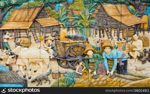 Stone carving of traditional Thai rural culture on temple wall