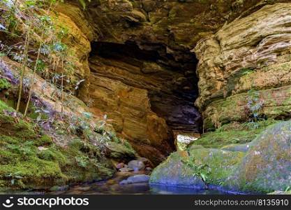 Stone cave interior with small river and lake surrounded by vegetation of Brazilian jungle. Rainforest cave interior with small river and lake
