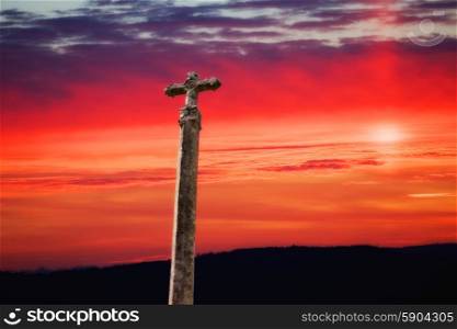 stone cross with the sunset as background