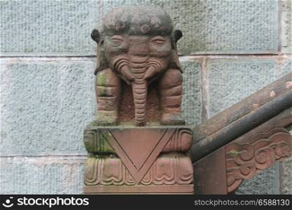 Stone elephant near wall in buddhist temple, China