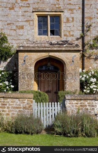 Stone farmhouse doorway with white roses, and garden gate.