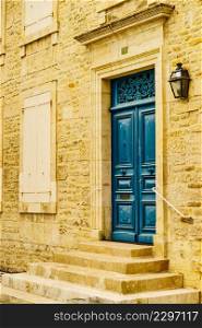 Stone house facade with old wooden dark blue entrance door and shutters window. Architecture in France.. Stone house with blue door and shutters window