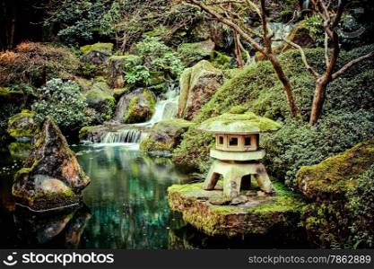 Stone lantern on a koi pond with a small waterfall.