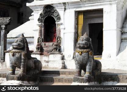 Stone lions near white stupa in Patan, Nepal