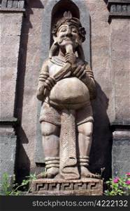 Stone man with long beard near entrance of temple, bali
