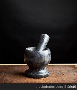 stone mortar with pestle for grinding spices on a brown wooden board, low key