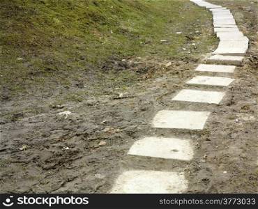 Stone path trail climbing through a muddy dirty park, brick sidewalk