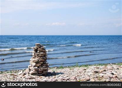 Stone sculpture by the beach with waves and blue water