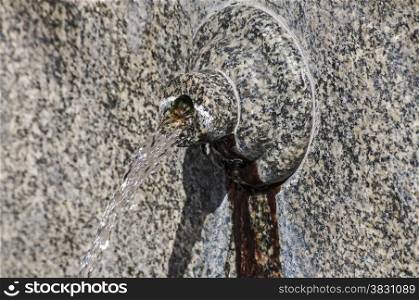 Stone spout of fountain with gushing thermal mineral water