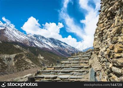 Stone stairs leading to the sky in the Himalayas, Nepal. Beautiful snowy mountain peaks and clouds. 