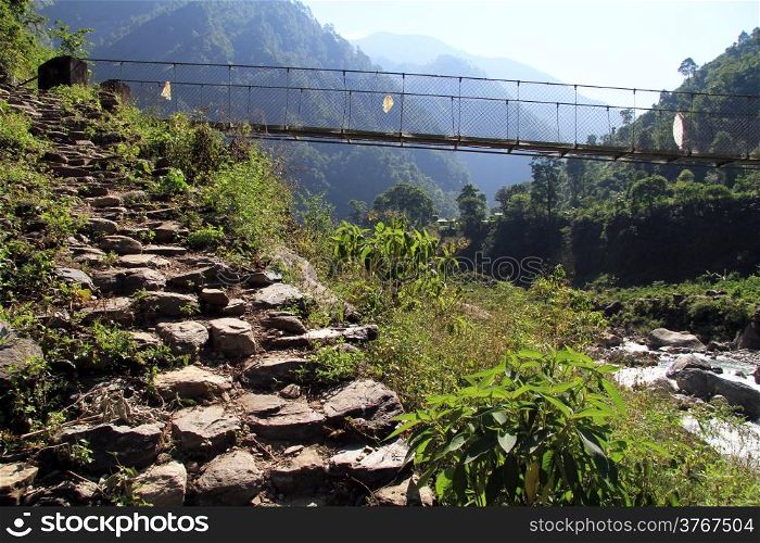 Stone steps and suspension bridge on the mountain river in Nepal