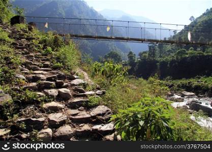 Stone steps and suspension bridge on the mountain river in Nepal