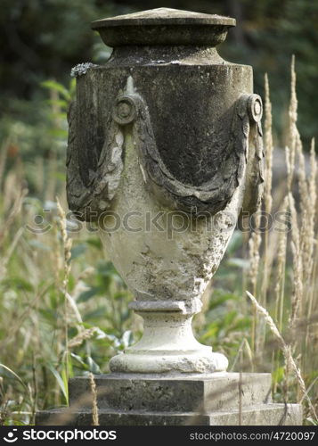 Stone urn. Urn in stone in the grass on the forest cemetery
