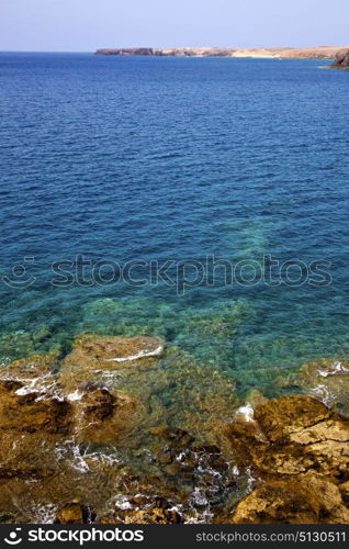 stone volcanic spain water coast in lanzarote sky cloud beach and summer