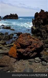 stone volcanic spain water coast in lanzarote sky cloud beach and summer