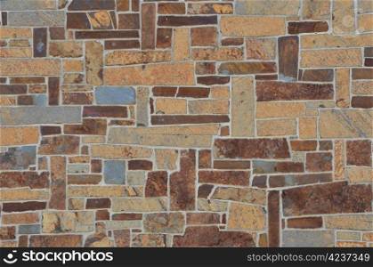Stone wall in multi colors of gray, brown, and tan.