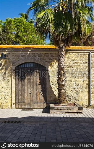 Stone wall with old gate decorated with palm tree in Tel Aviv. Israel historic warehouse on the line from Tel Aviv to Jerusalem