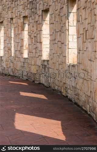 Stone wall with windows on it. Brick wall with sunshine.