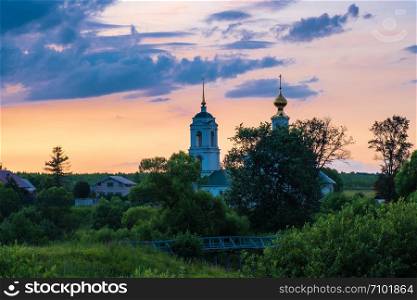 Stone white church with a bell tower against the evening sky, Russia.