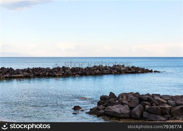 stones breakwater near beach of Giardini Naxos resort in Ionian Sea, Sicily