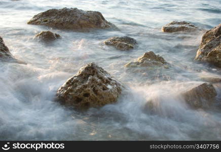 stones in sea water washing by waves, long exposure