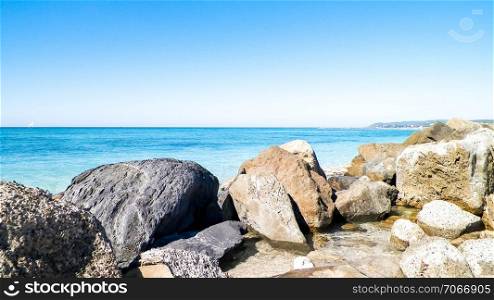 Stones on the beach in Vada, transparent, turquoise water and white sand. Travel and nature concept.. Stones on beach in Vada, Italy.