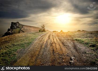Stony road in mountains at the sunset