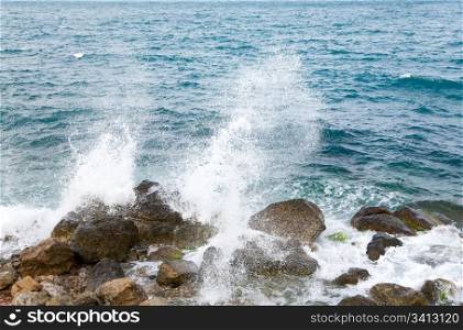 Stony sea coastline and wave with splashes