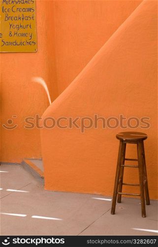 Stool beside orange wall in Santorini Greece