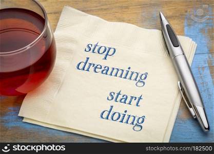 Stop dreaming, start doing - inspirational handwriting on a napkin with a cup of tea