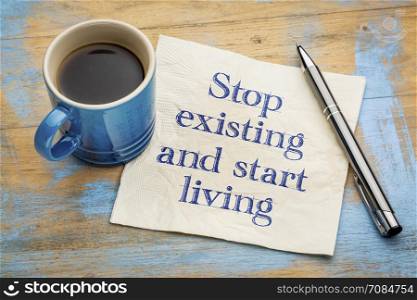 Stop existing and start living - handwriting on a napkin with a cup of espresso coffee