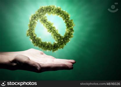 Stop pollution. Close up of human hand holding green prohibition sign