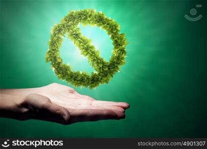 Stop pollution concept. Close up of human hand holding green prohibition sign
