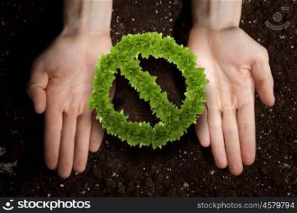 Stop pollution concept. Close up of human hands holding green prohibition sign