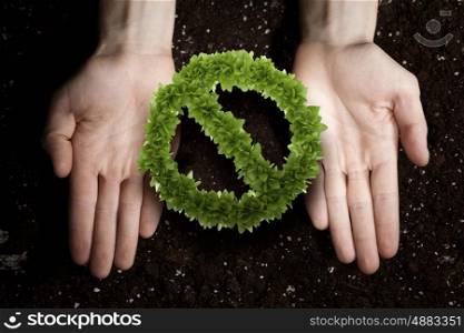 Stop pollution concept. Close up of human hands holding green prohibition sign
