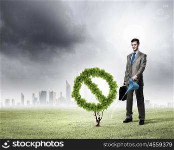 Stop pollution. Image of businessman watering plant shaped like prohibition symbol