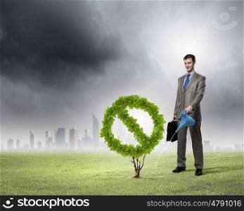 Stop pollution. Image of businessman watering plant shaped like prohibition symbol
